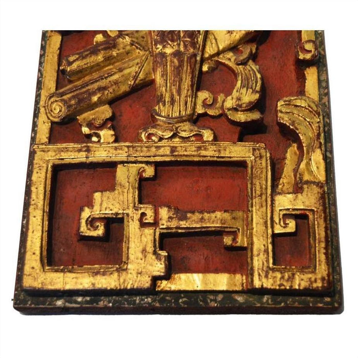 Close-up of an antique Chinese hand-carved temple ornament with gold geometric and scroll designs on vivid red wood.