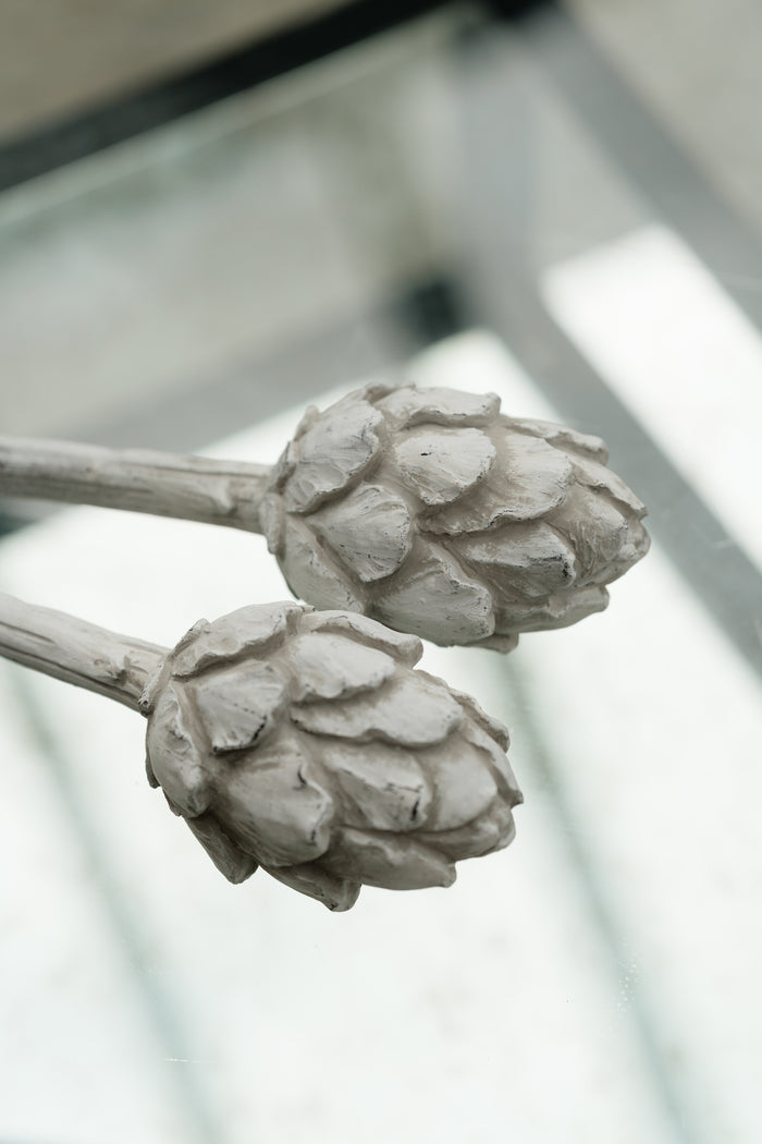 Two gray artichoke-shaped objects on a blurred background