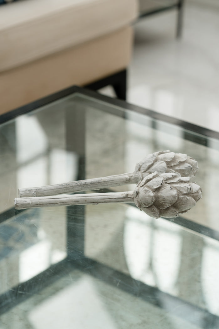 Decorative artichoke sculpture on a glass table with a blurred background
