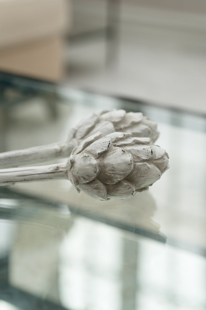Decorative artichoke sculpture on a glass surface with a blurred background