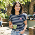 Woman in a striped shirt holding a green mug outdoors
