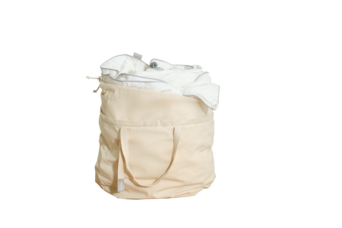 Beige canvas laundry bag filled with white fabric, featuring handles and an external pocket.