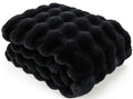 A folded black faux fur blanket with a wavy, tufted texture, shown on a clean white background.