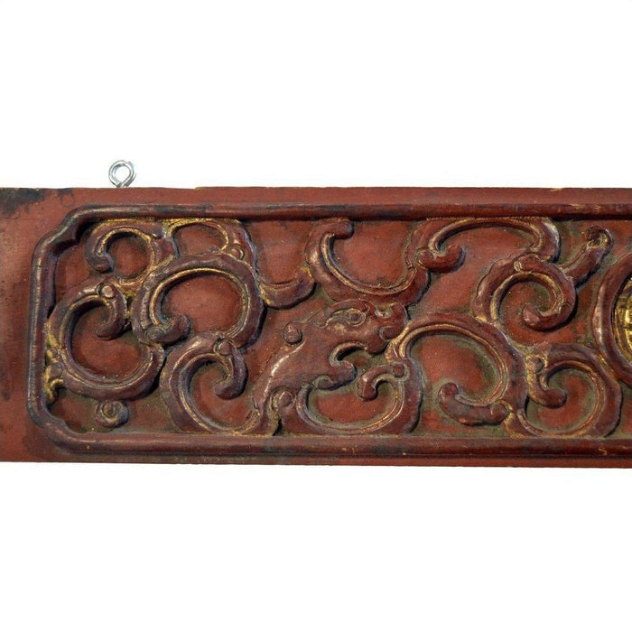 Close-up of a Chinese hand carved wood plaque featuring swirling floral patterns in muted gold and brown tones.