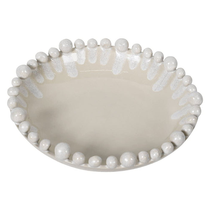 An oval ceramic dish with a glossy cream finish, featuring a raised border of white beads and textured white drips around the rim, shown on a plain white background.