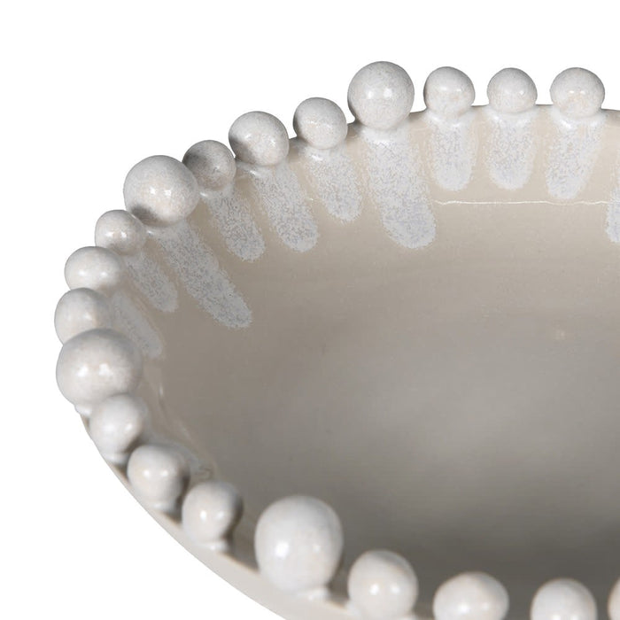 Close-up of a ceramic bowl with a glossy off-white interior and a beaded rim featuring a textured, slightly darker white glaze, set against a plain white background.