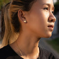 Close-up of a woman wearing a gold earring and necklace outdoors