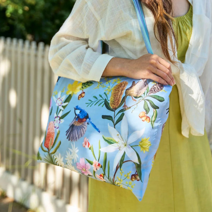 Person holding a floral and bird-patterned bag outdoors