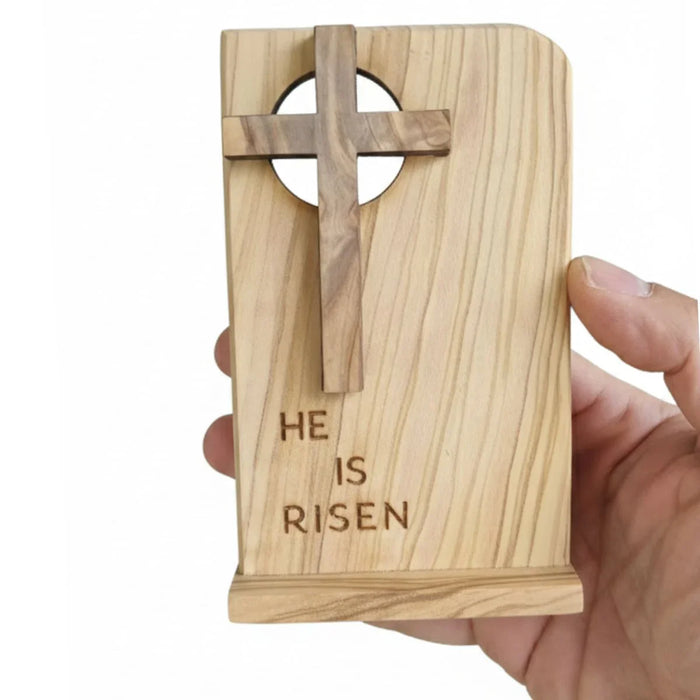 Wooden cardholder with cross design and 'HE IS RISEN' engraving held by a hand on a white background