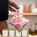 Pantry pest repellent held up by a feminine hand with a blurred pantry in the background.