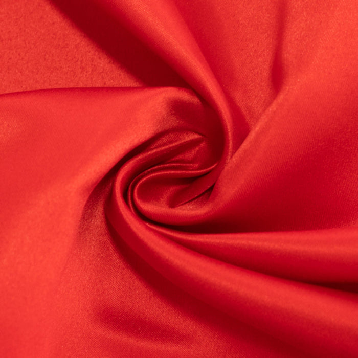 Red satin fabric with a smooth, lustrous finish, elegantly twisted. #whtbkgd