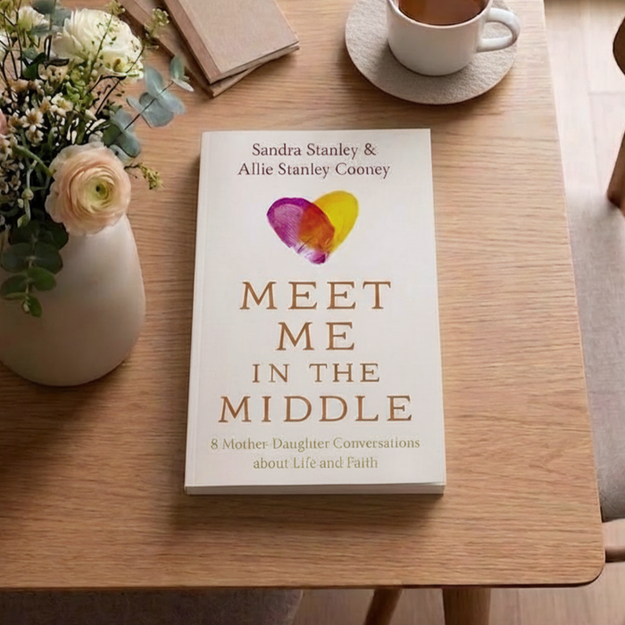 Book 'Meet Me in the Middle' by Sandra Stanley and Allie Stanley Cooney with colorful hearts on a dining table.