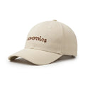 A cream Novomins baseball cap shown at a three-quarter angle on a white background, with the novomins wordmark embroidered in brown across the front panel.