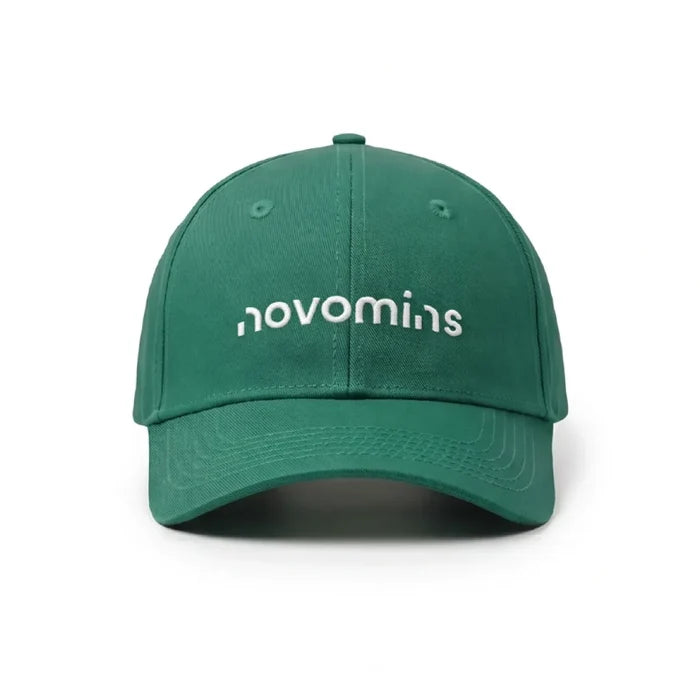 Front view of a green Novomins baseball cap on a white background, with the novomins wordmark embroidered in white across the front panel.