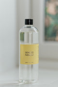 A clear glass bottle of Senses Neroli fragrance oil with a pale yellow label and a black cap, standing on a light surface against a softly blurred background.