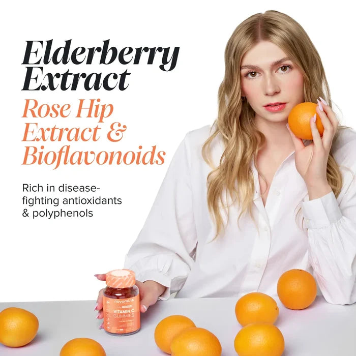 A woman in a white shirt holds an orange at a table scattered with oranges and a bottle of Novomins Vitamin C Gummies, headed 'Elderberry Extract, Rose Hip Extract & Bioflavonoids, rich in disease-fighting antioxidants and polyphenols'.