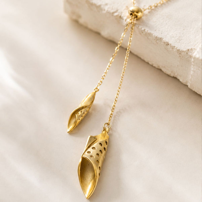 Gold necklace with leaf-shaped pendants on a light background