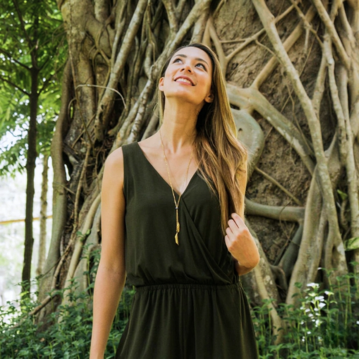 Woman in a black dress standing in front of a large tree with intricate root system